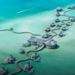 Aerial view of overwater villas in a Maldives atoll — staying at The Ritz-Carlton Maldives with Bitcoin